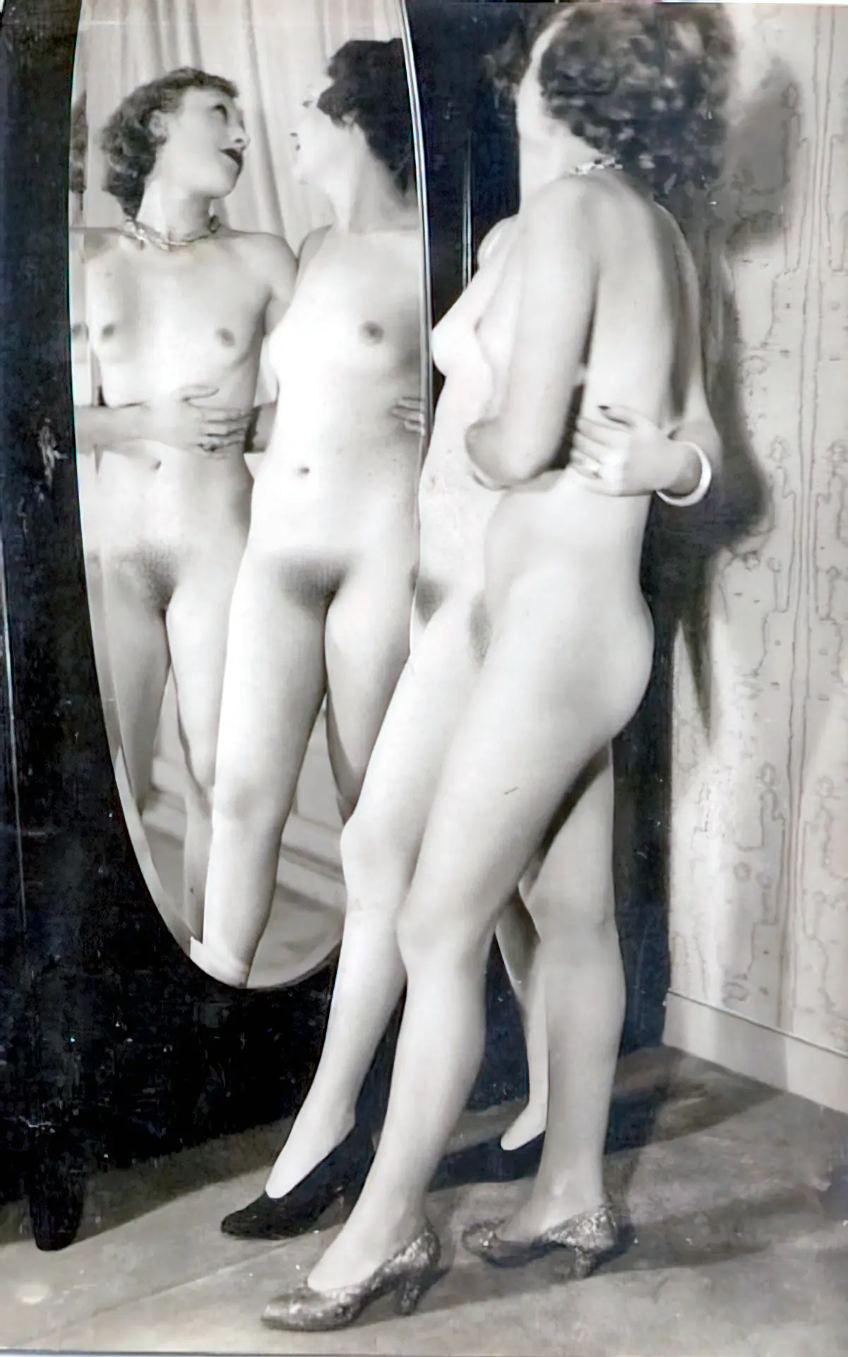 Two embraced retro ladies with small tits stand in front of the mirror