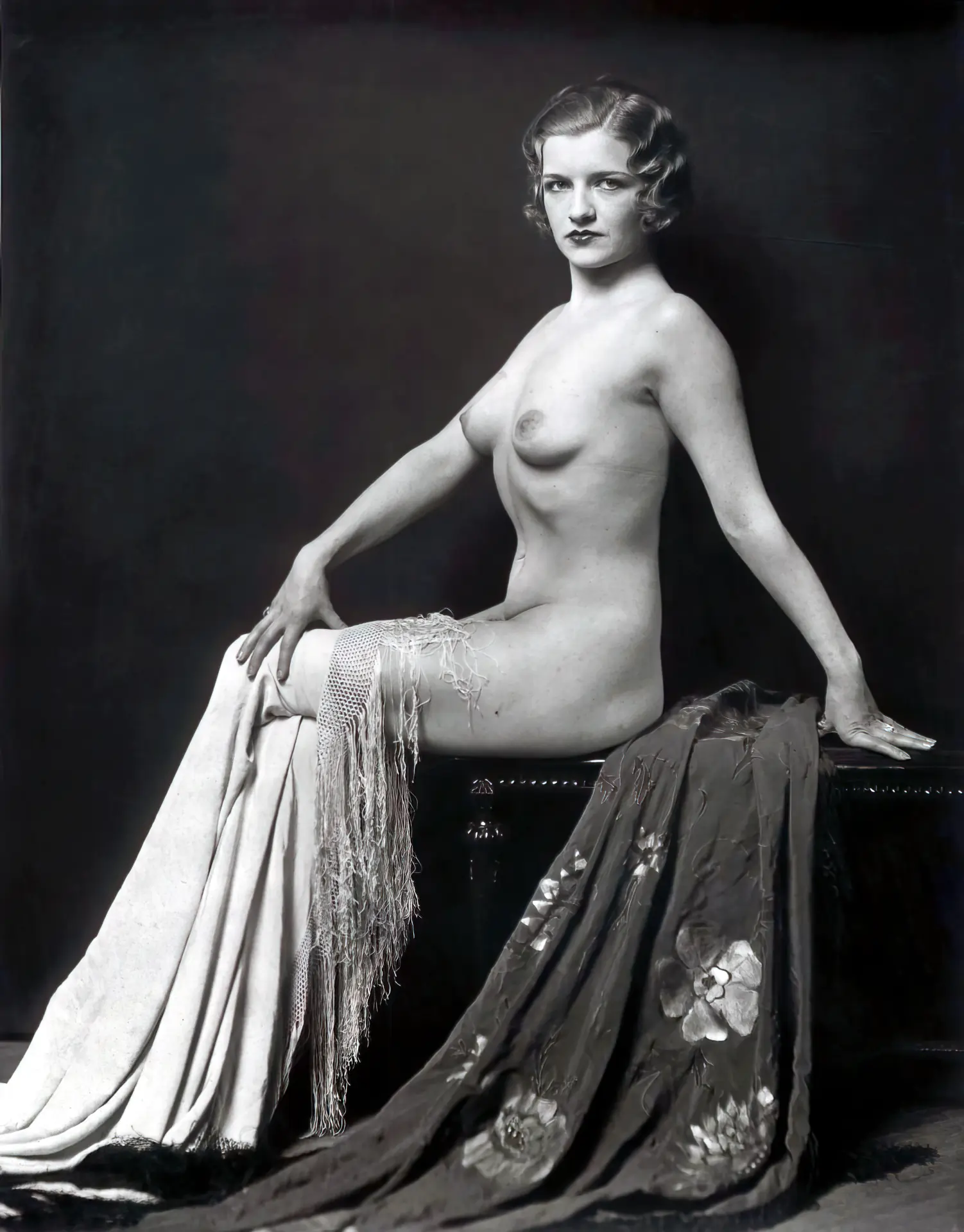 Graceful blonde with a vintage hairstyle poses naked on a chair