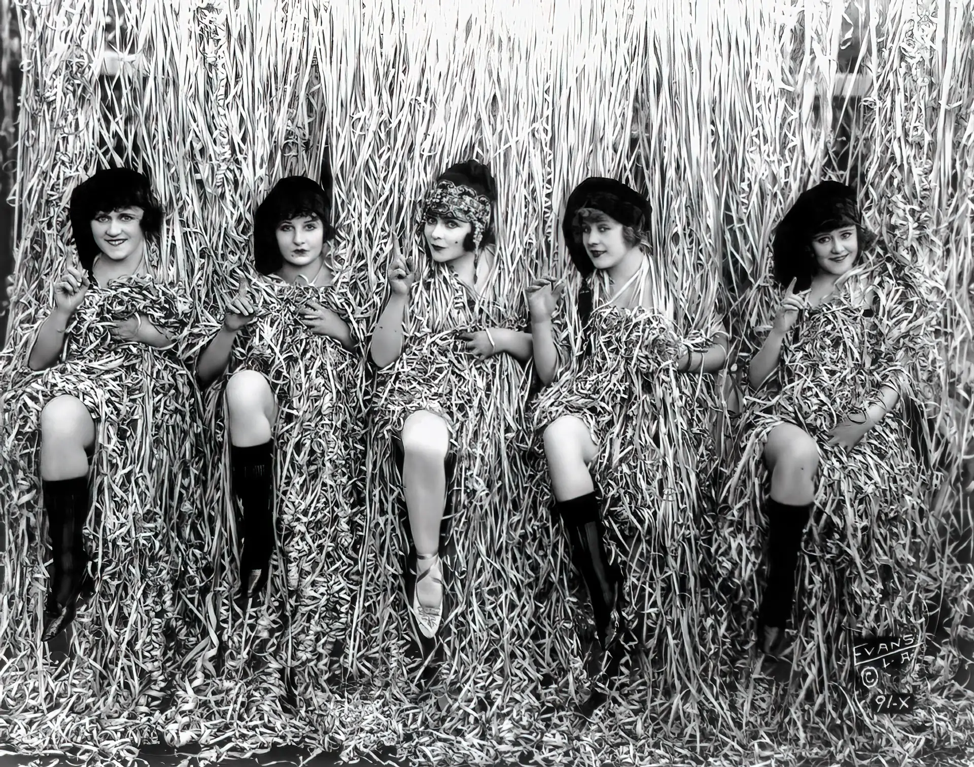 A bunch of burlesque ladies hide behind hanging straps