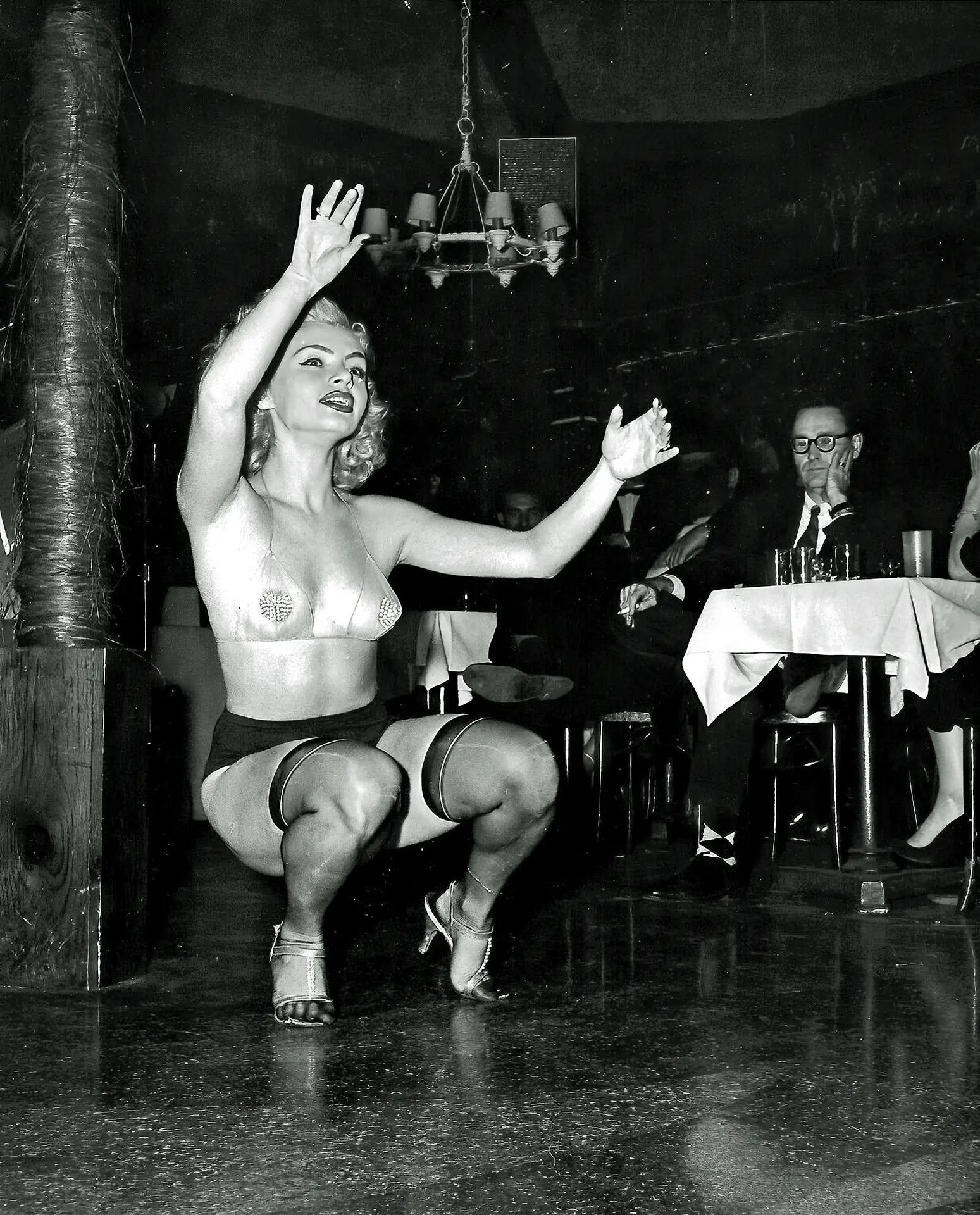 Vintage burlesque porn photos with skimpy dressed blonde woman in stockings and a transparent bra dancing on the stage of the nightclub