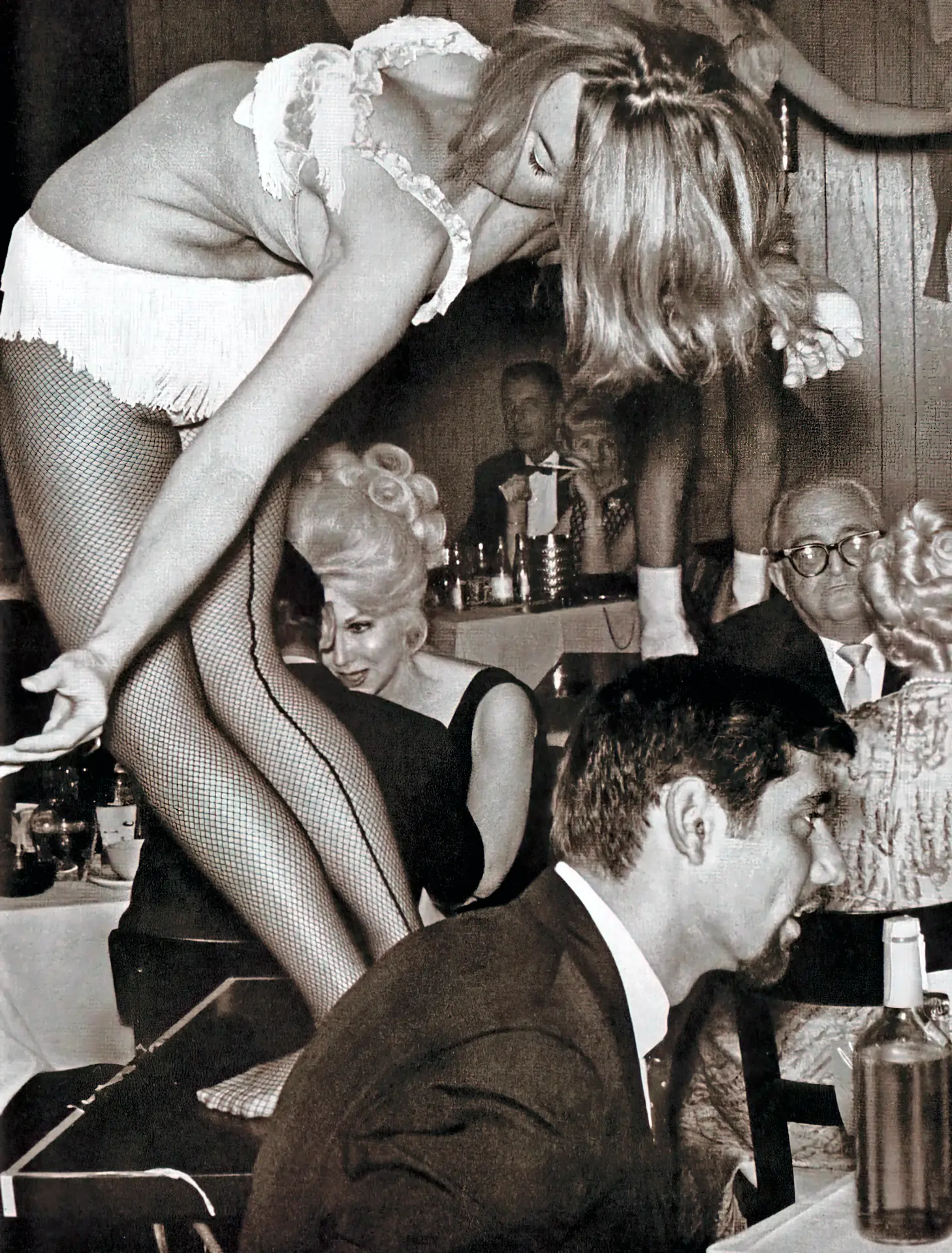 Vintage stripper porn photo Burlesque girl in white undies dances on the table in a room full of people