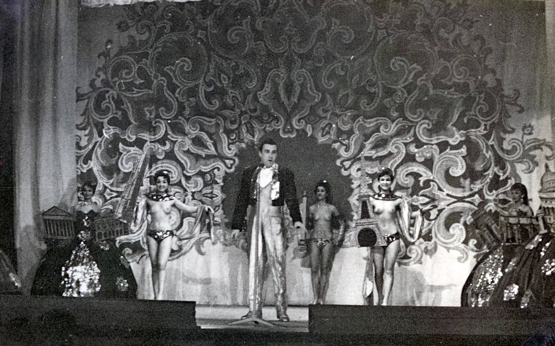 Burlesque man introduces three topless babes to the audience