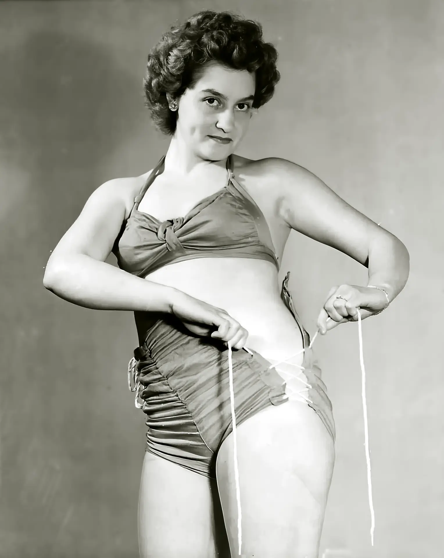 Older burlesque lady with curves tries to tie her bikini