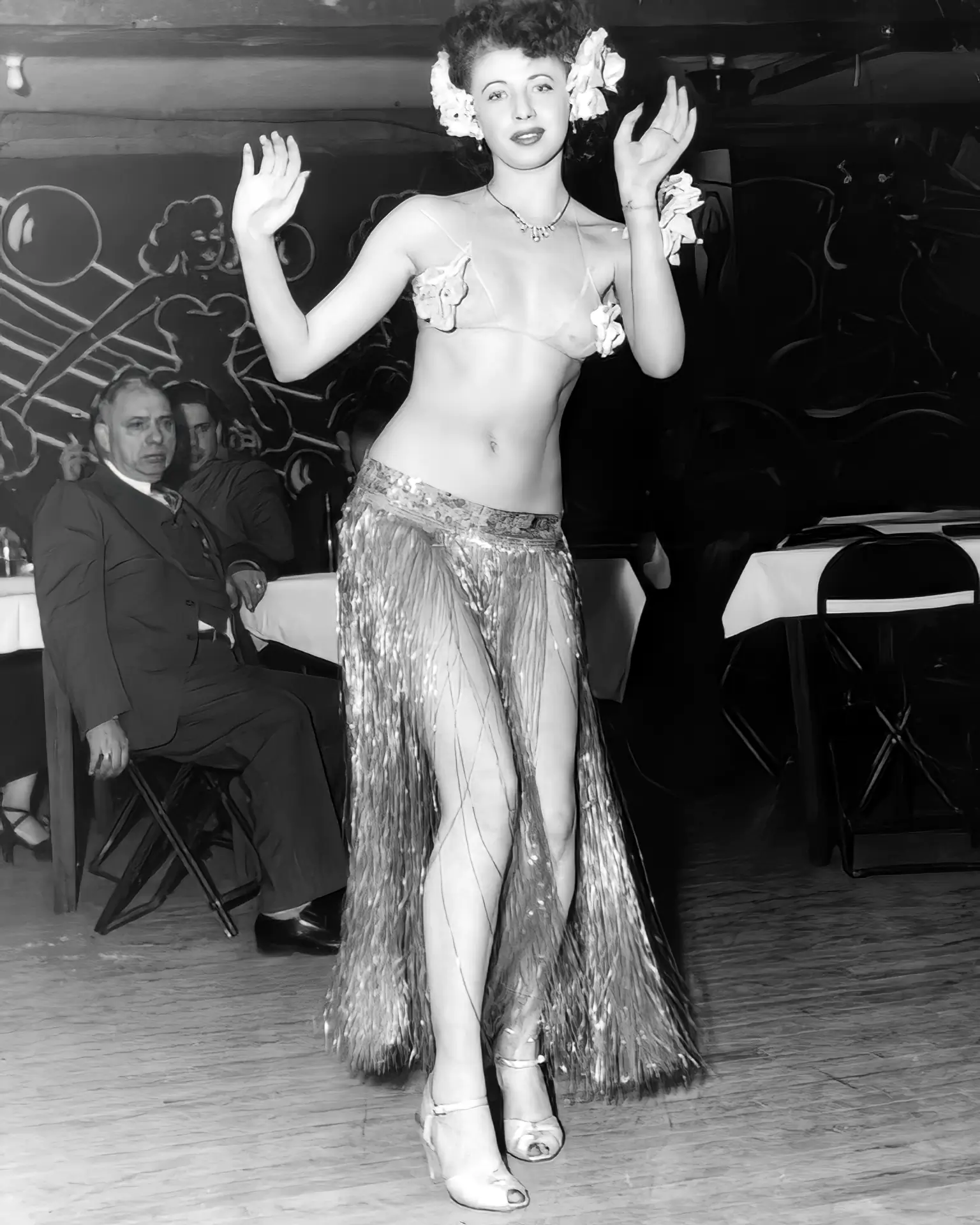 Skinny burlesque lady dances in a room full of men in her lambada skirt