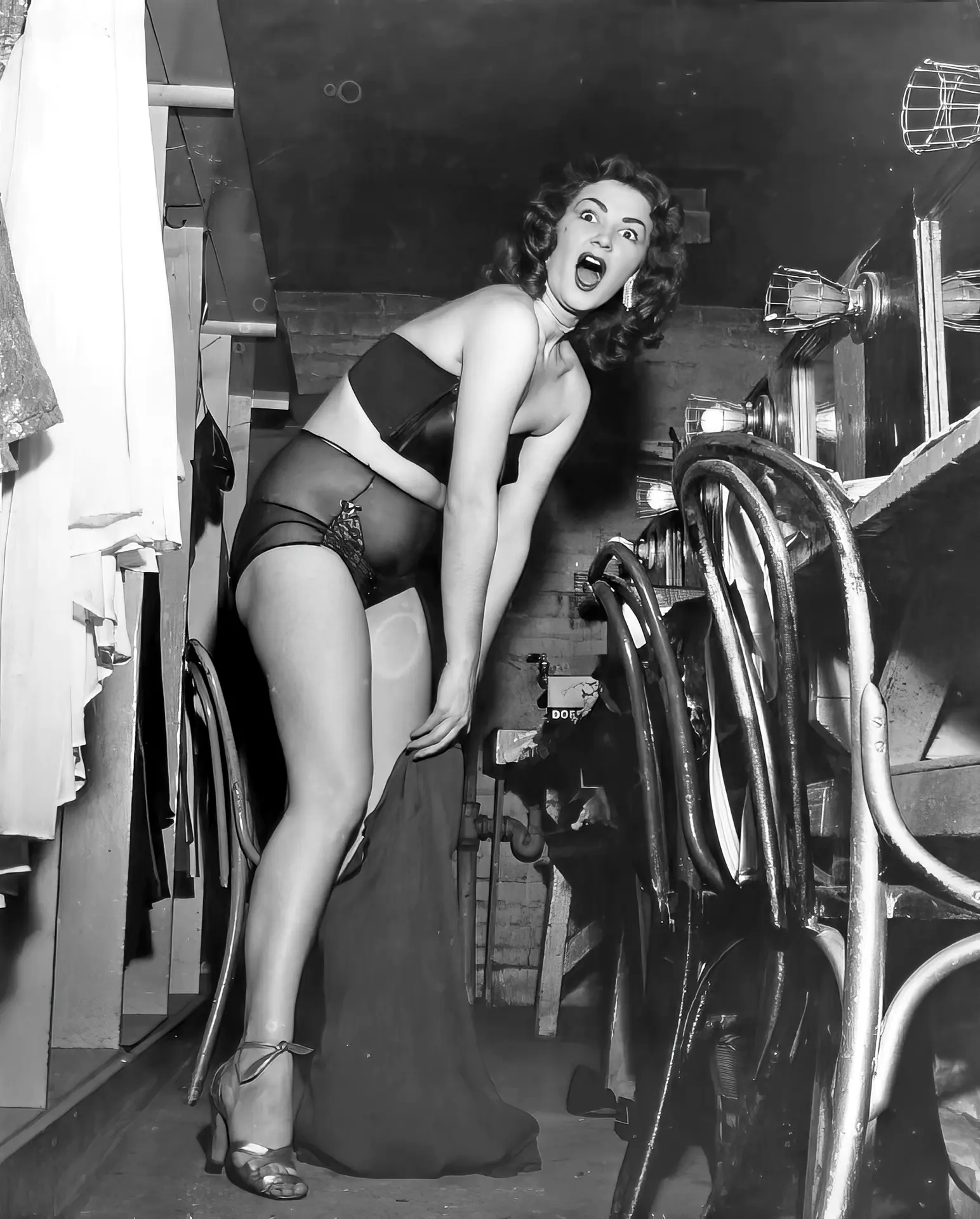 Surprised vintage burlesque dancer tries to put on her clothes