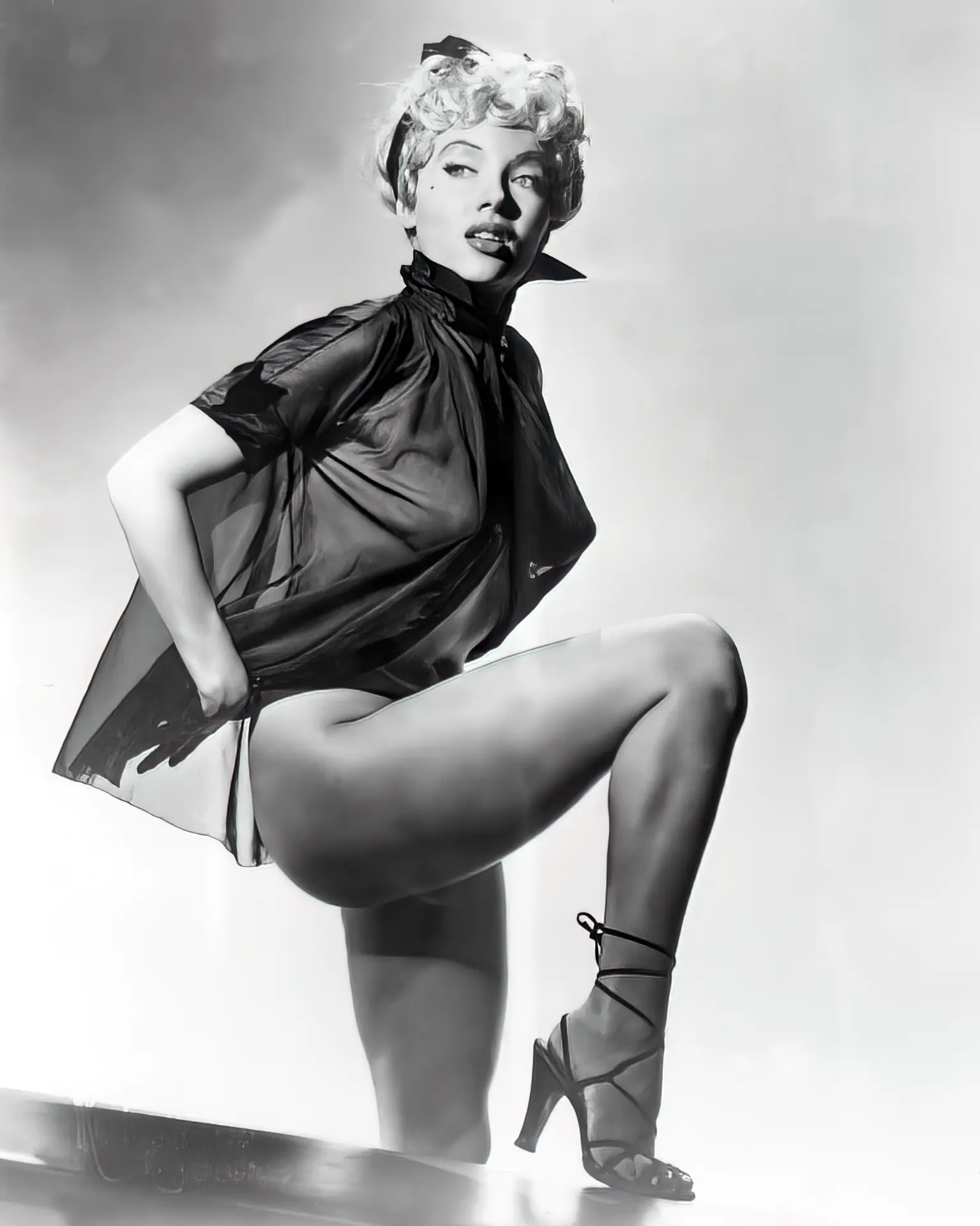 Lili St. Cyr poses in a silky blouse and heels
