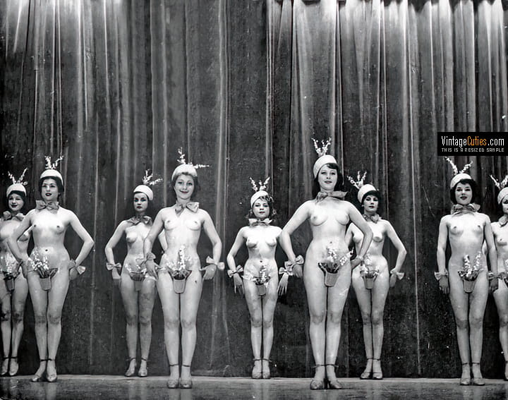 Burlesque girls stand topless on the stage with their pussies covered.